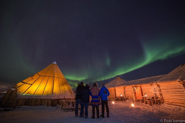 Cena in un accampamento di renne e aurora boreale