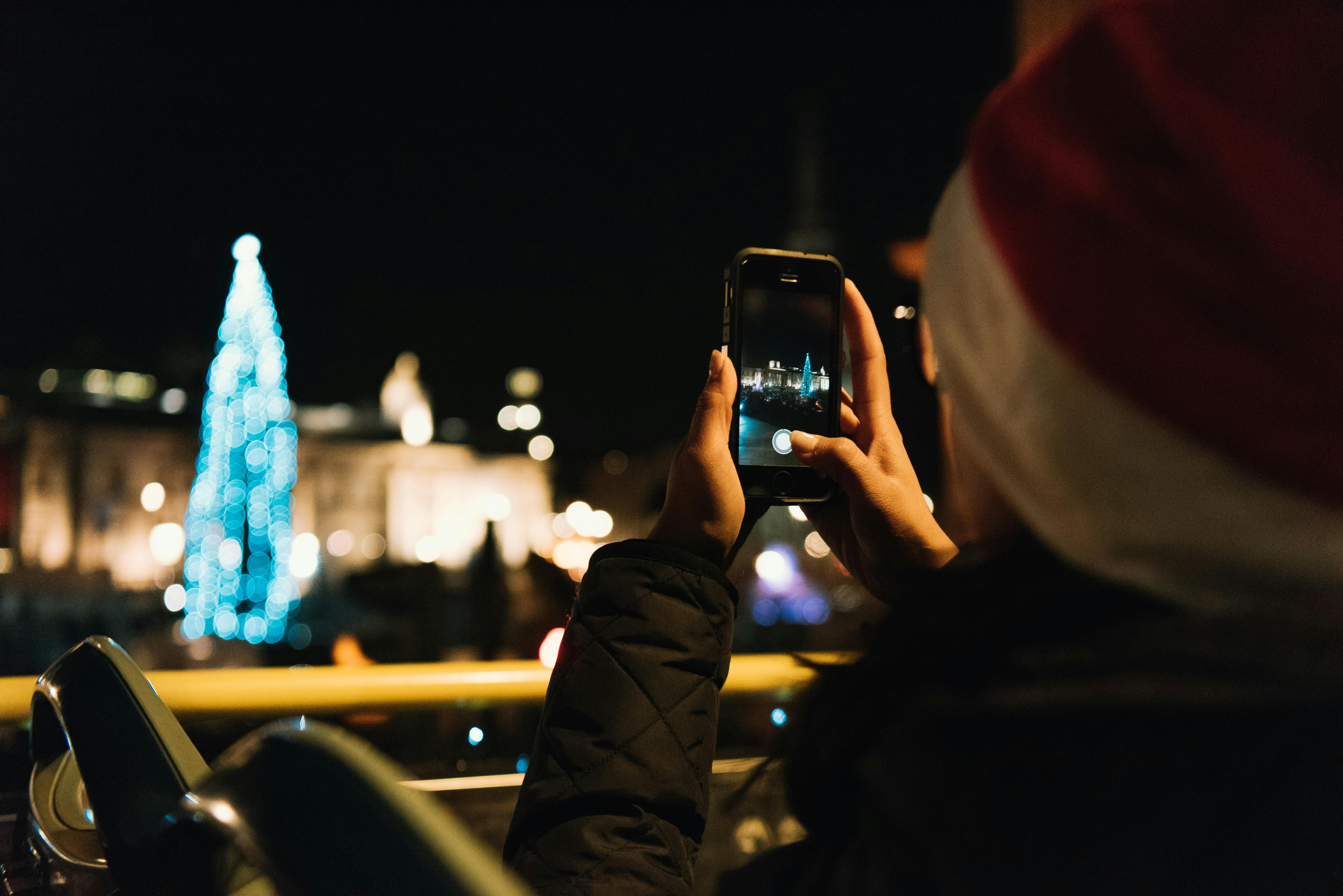Girl in Santa hat photographing a Christmas tree.jpg