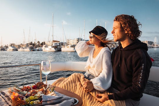 Cruise bij zonsondergang op een elektrische boot met een bord met wijn en charcuterie