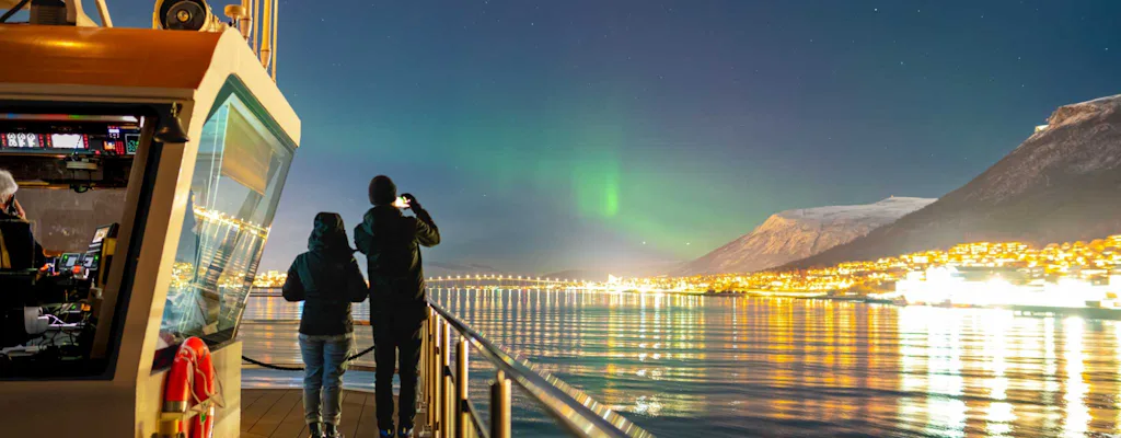 Northern lights visible over Tromsø waters during a night cruise