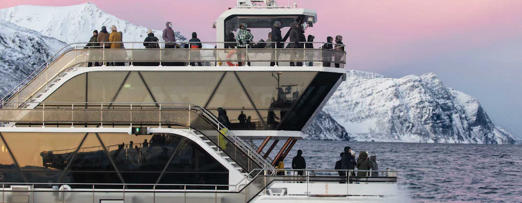 Modern cruise boat in Tromsø fjord with snowy mountains in the background