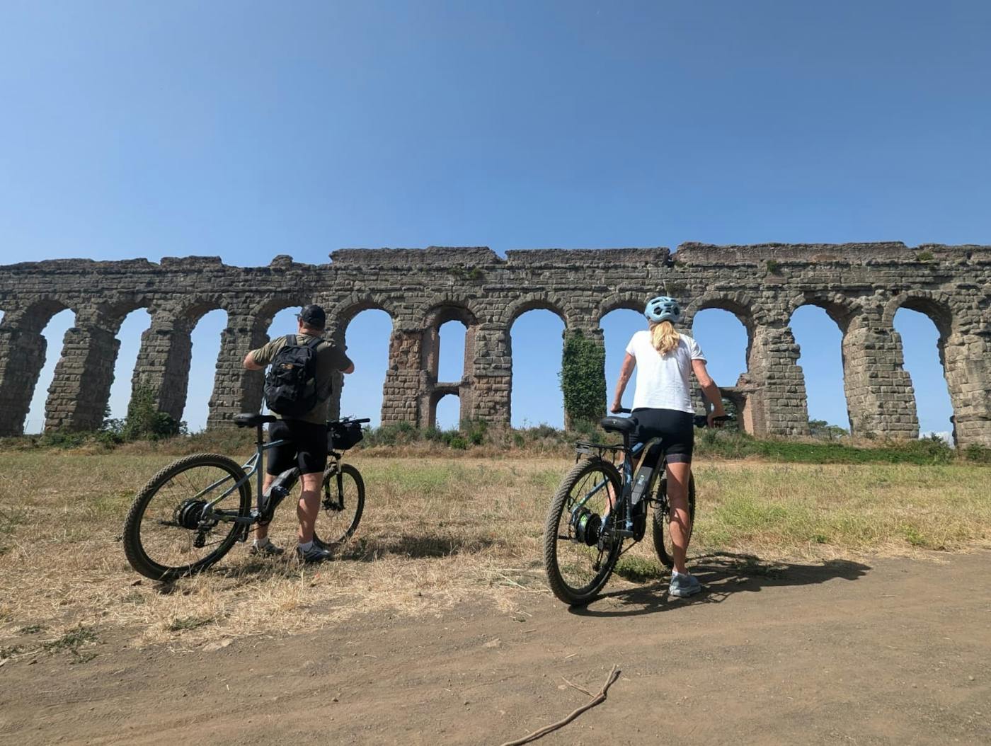 Cyclists with e-bikes near Rome's ancient aqueducts on a nature-focused route