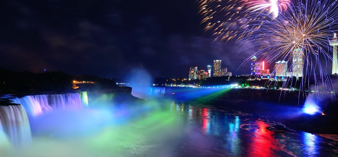 Niagara Falls illuminated at night with fireworks during the Toronto to Niagara Falls evening tour