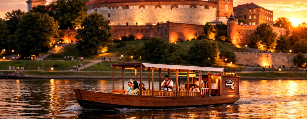 Wooden gondola cruising past illuminated Wawel Castle in Krakow at sunset