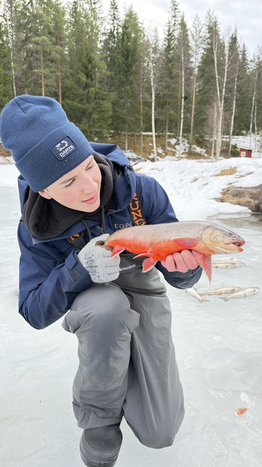 Ice fishing on frozen water with local guide