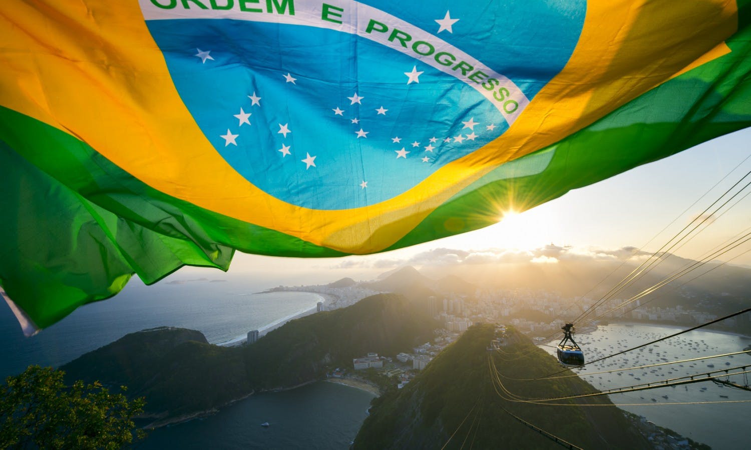 Brazilian flag shines above the golden sunset city skyline at Sugarloaf Pao de Acucar Mountain in Rio de Janeiro Brazil.jpg