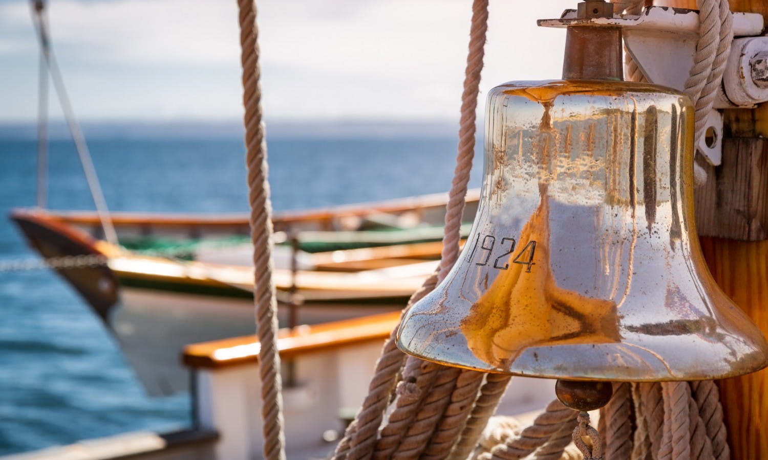 Brass ship bell on a classic big wooden sailboat at sea. Close up.jpg